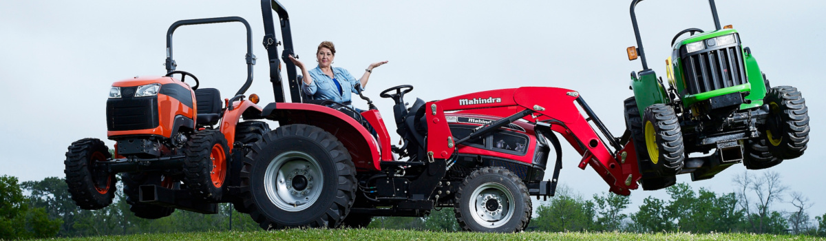 2017 Red Mahindra Tractor balancing two tractors over green grass